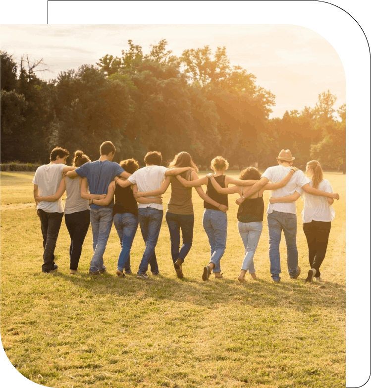 A group of people standing in the grass with their arms around each other.