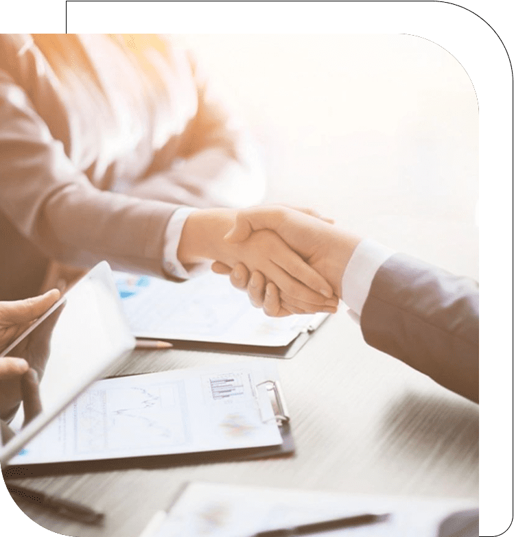 Two people shaking hands over a table.